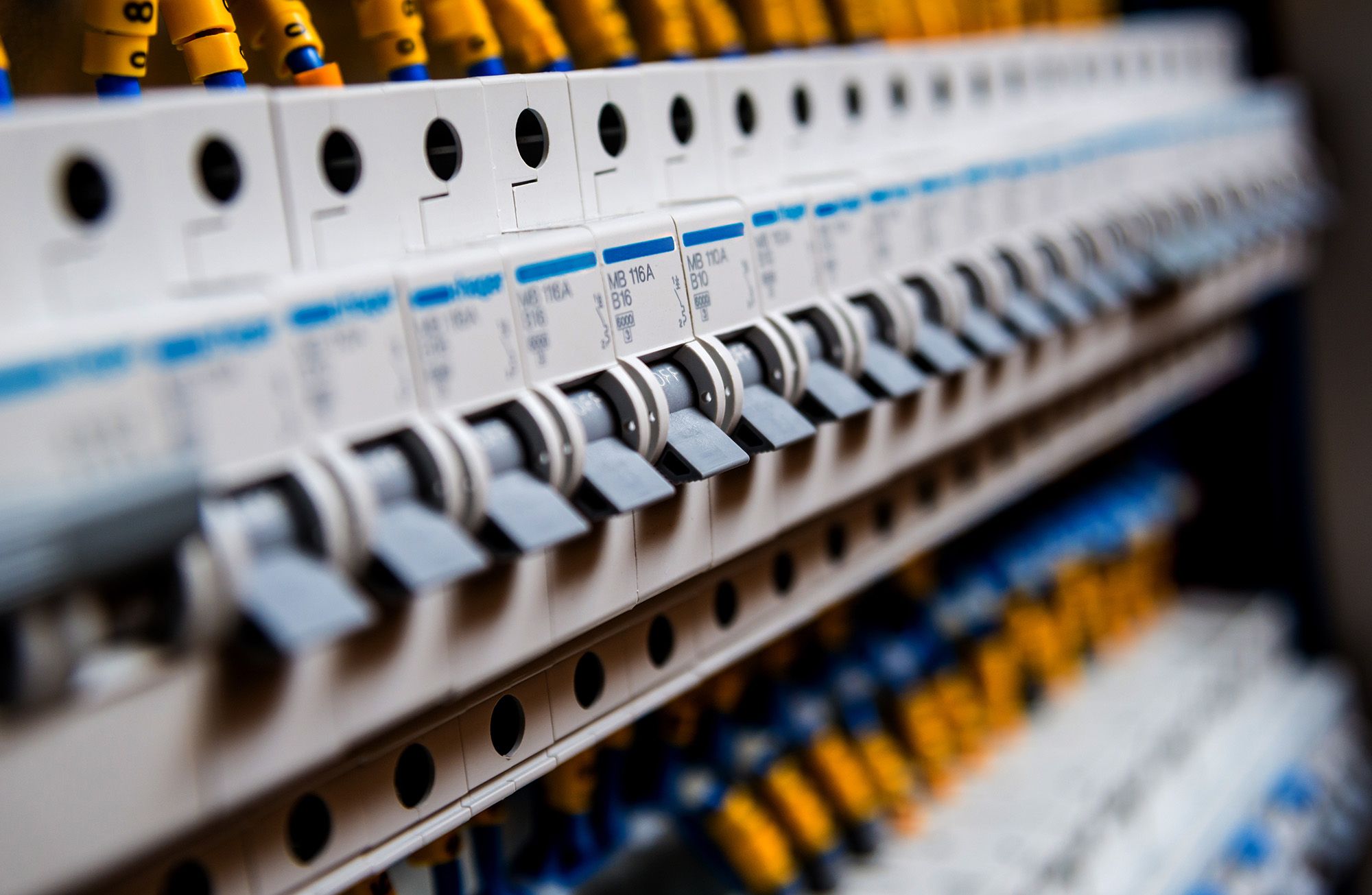 Detailaufnahme eines elektrischen Panels, das gelbe und blaue Kabel zeigt, die miteinander verbunden sind.
